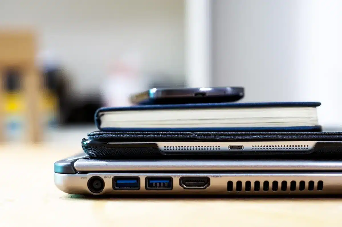 Hands over laptop and smartphone displaying generic cryptocurrency charts on a newsroom desk