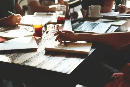 Editor workspace with laptop, notepad and pen on a sunlit desk
